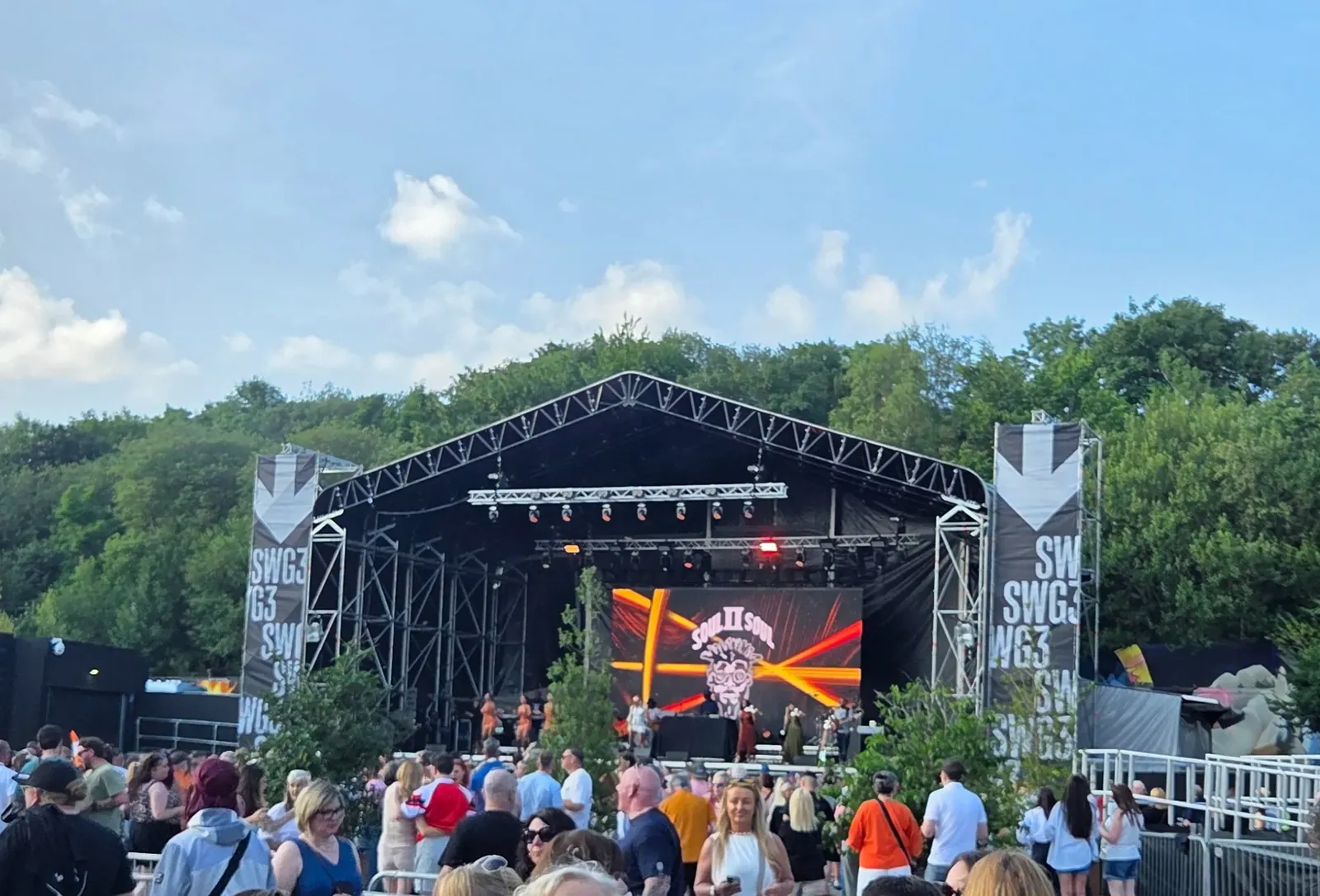 An outdoor festival stage with SWG3 banners and a crowd in front of it